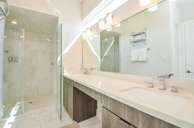 a bathroom with a double vanity sink mirror and shower