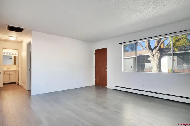 a view of an empty room with a window and wooden floor
