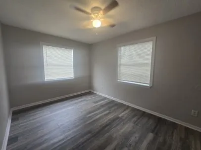 a view of an empty room with a window and wooden floor