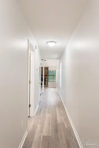 a view of an empty room with wooden floor fireplace and a window