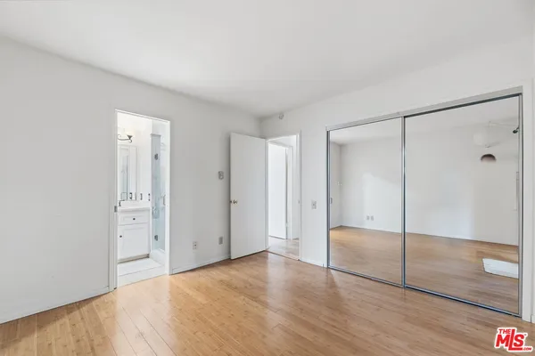a view of an empty room with wooden floor and a bathroom