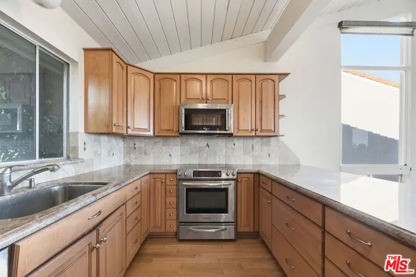 a kitchen with granite countertop a sink stainless steel appliances and cabinets