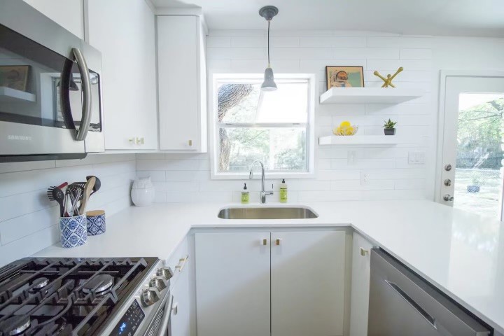 a kitchen with stainless steel appliances a sink a stove and a window