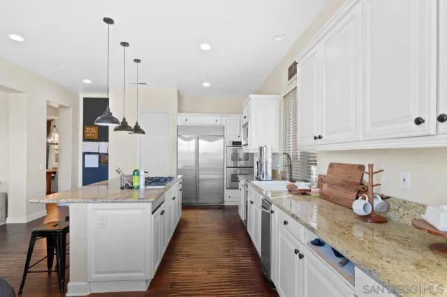 a kitchen with granite countertop a stove a sink a center island with a dining table and chairs