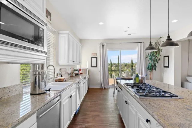 a kitchen with stainless steel appliances granite countertop a sink dishwasher and white cabinets with wooden floor