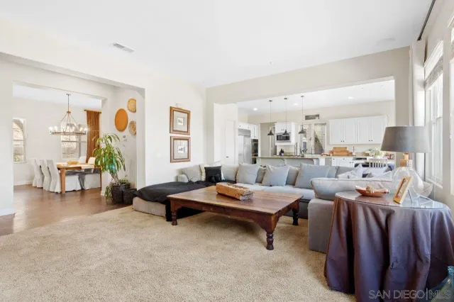 a kitchen with stainless steel appliances kitchen island granite countertop a dining table chairs and white cabinets