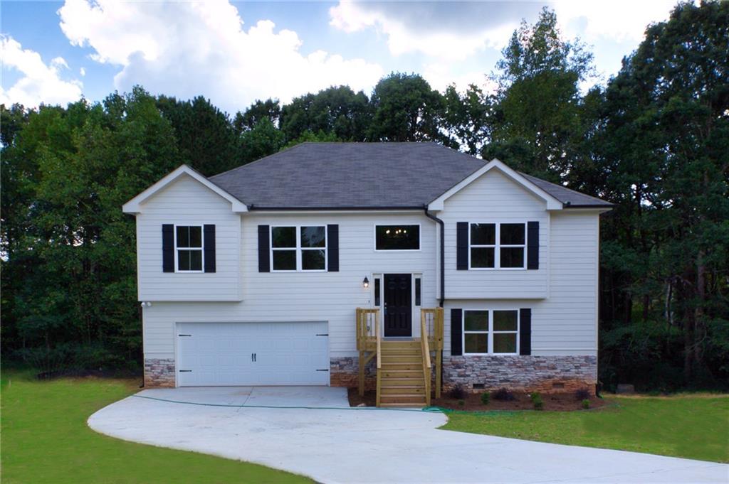 a view of a yard in front of a house with plants and large tree