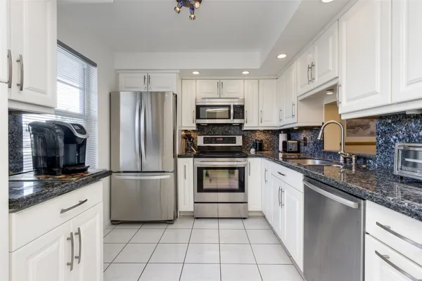 a kitchen with granite countertop a refrigerator and a sink