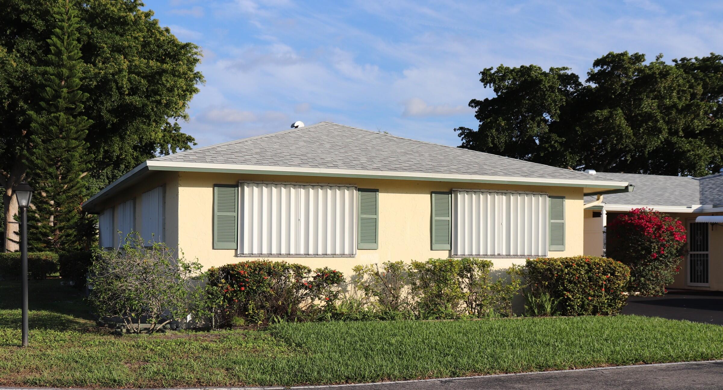 201 Cardinal Lane Delray Beach, FL 33445 - Photo 2 of 20 a front view of a house with a garden and plants
