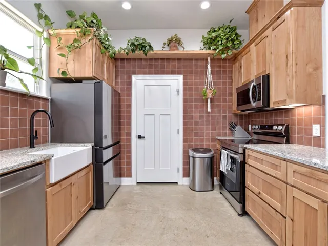 a kitchen with stainless steel appliances granite countertop a refrigerator a stove top oven a sink and dishwasher