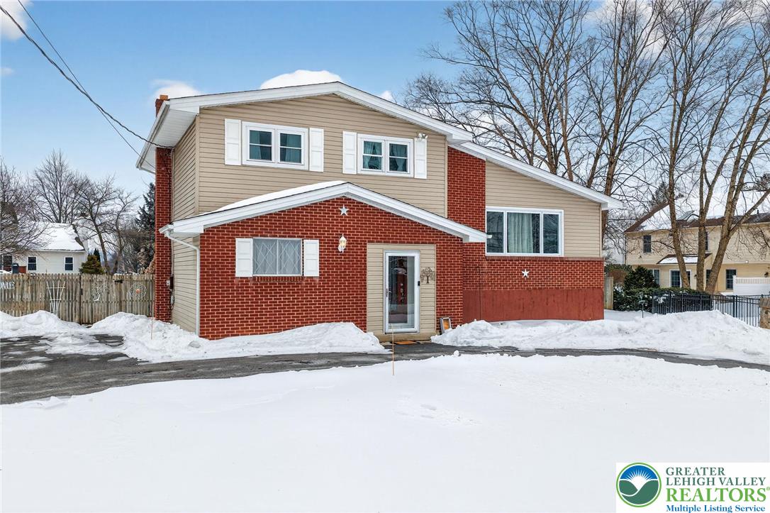 a front view of a house with a yard covered in snow