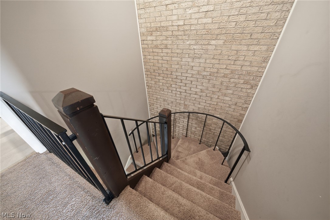 824 South Chillicothe Road, Unit 2 Aurora, OH 44202 - Photo 29 of 42 Curved staircase featuring carpeted treads, a dark wood-finish newel post, and black wrought iron balusters