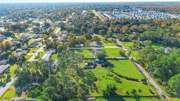 an aerial view of residential houses with outdoor space and trees