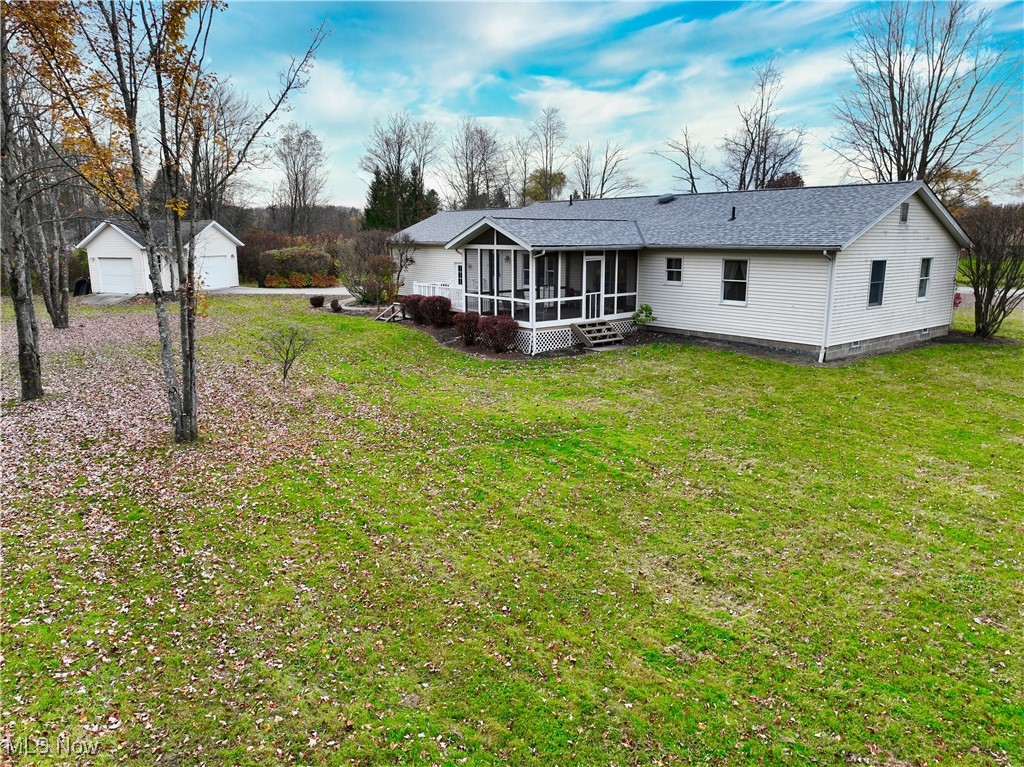 17161 Burrows Road Thompson, OH 44086 - Photo 41 of 48 Rear view of property with an outbuilding, a garage, a lawn, and a sunroom