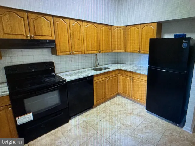 a kitchen with granite countertop stainless steel appliances a stove a refrigerator a sink and dishwasher with wooden cabinets