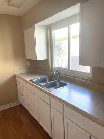 a kitchen with granite countertop a sink white cabinets and a large window