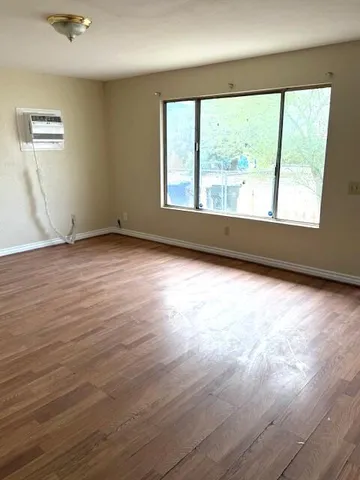 a view of an empty room with wooden floor and a window