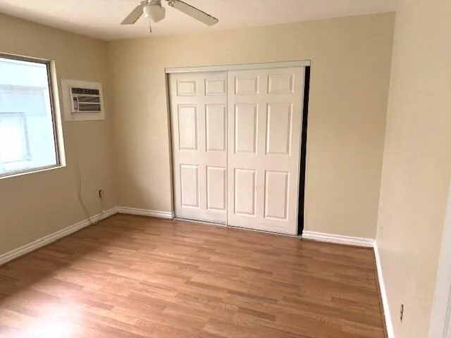 an empty room with wooden floor chandelier fan and windows