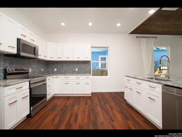 a kitchen with cabinets wooden floor and stainless steel appliances