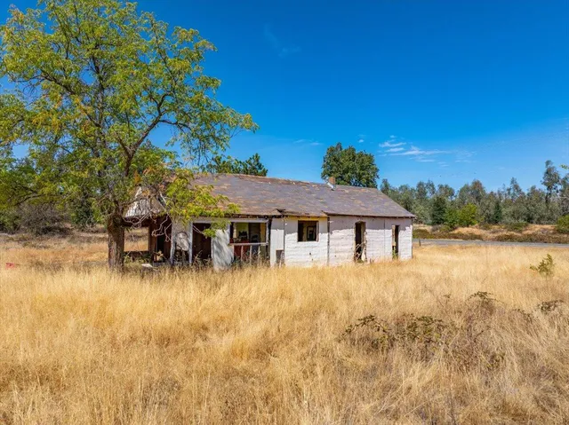 a backyard of a house with table and chairs under an umbrella