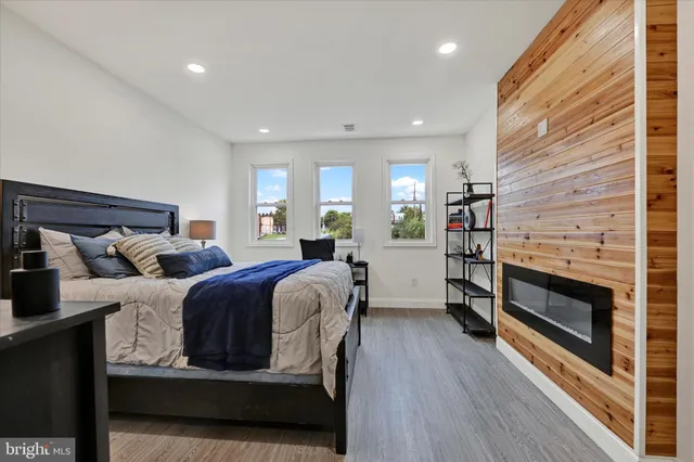 a living room with a bed furniture a fireplace and a wooden floor