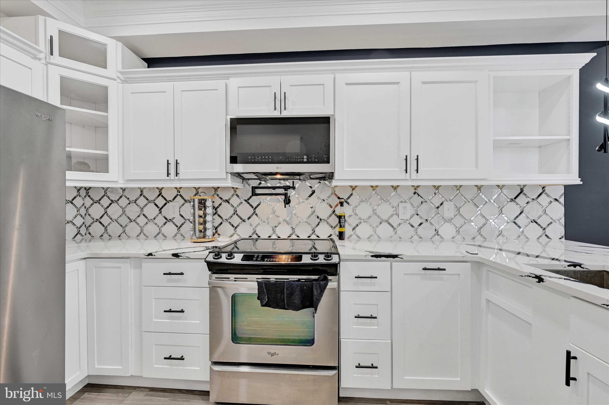 1748 North Chester Street Baltimore, MD 21213 - Photo 9 of 27 a kitchen with granite countertop white cabinets and black stove top oven