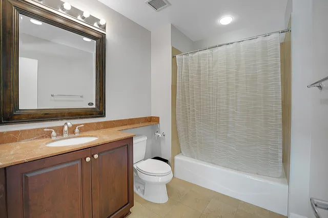 a bathroom with a granite countertop sink a toilet and shower