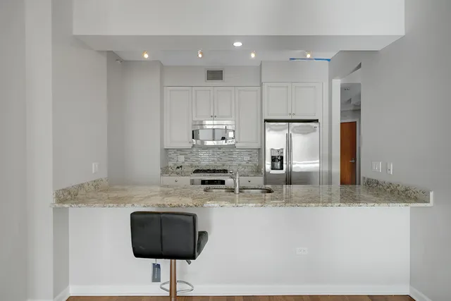 a kitchen with kitchen island granite countertop a counter space cabinets and stainless steel appliances