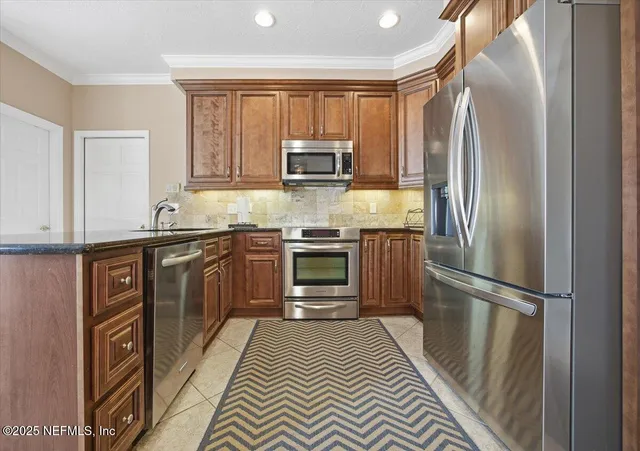 a kitchen with granite countertop stainless steel appliances a sink and a refrigerator