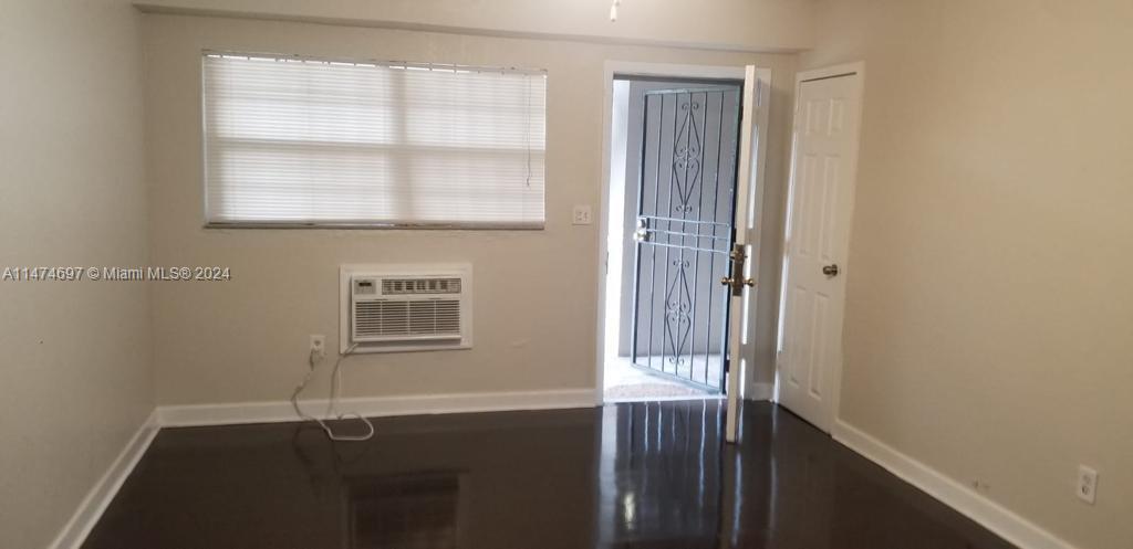 180 Northeast 71st Street, Unit 2 Miami, FL 33138 - Photo 3 of 10 a view of an empty room with wooden floor and a window
