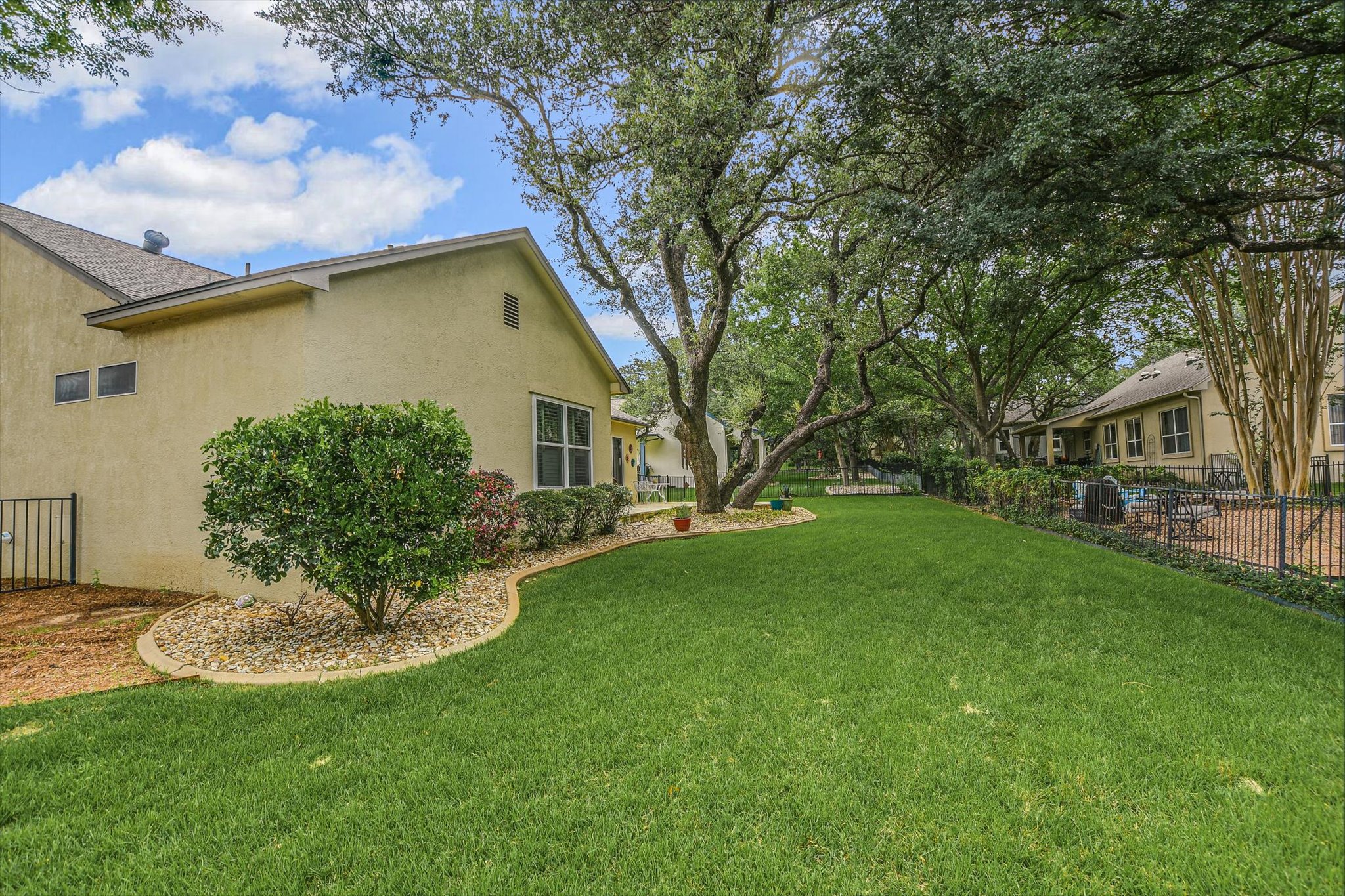 106 Nighthawk Way Georgetown, TX 78633 - Photo 28 of 29 A verdant backyard with mature trees and thoughtful landscaping borders a charming home.