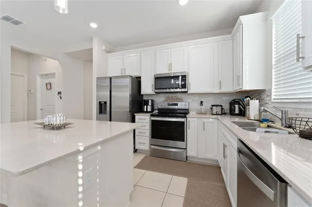 a kitchen with a sink a stove a refrigerator and white cabinets