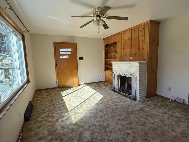 a view of an empty room with a fireplace and a window