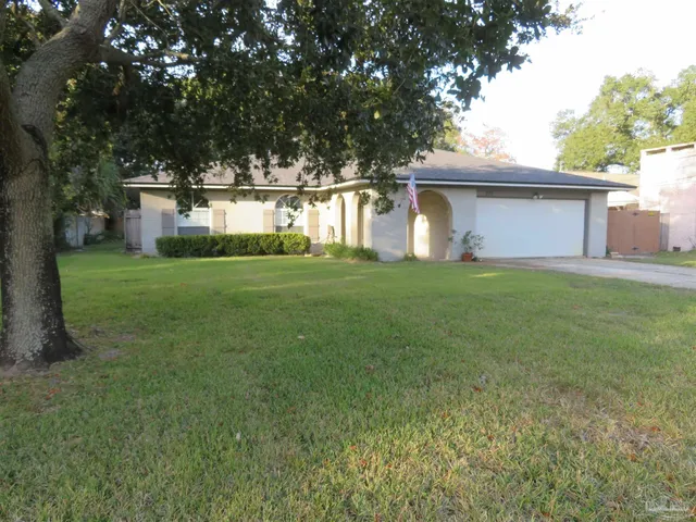 a view of a house with a yard and large trees