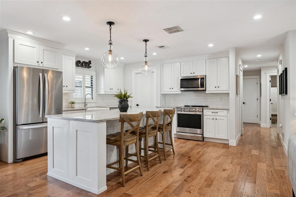 2609 Summerfield Road Winter Park, FL 32792 - Photo 14 of 40 a kitchen with kitchen island granite countertop a refrigerator oven a sink a stove and a dining table with wooden floor