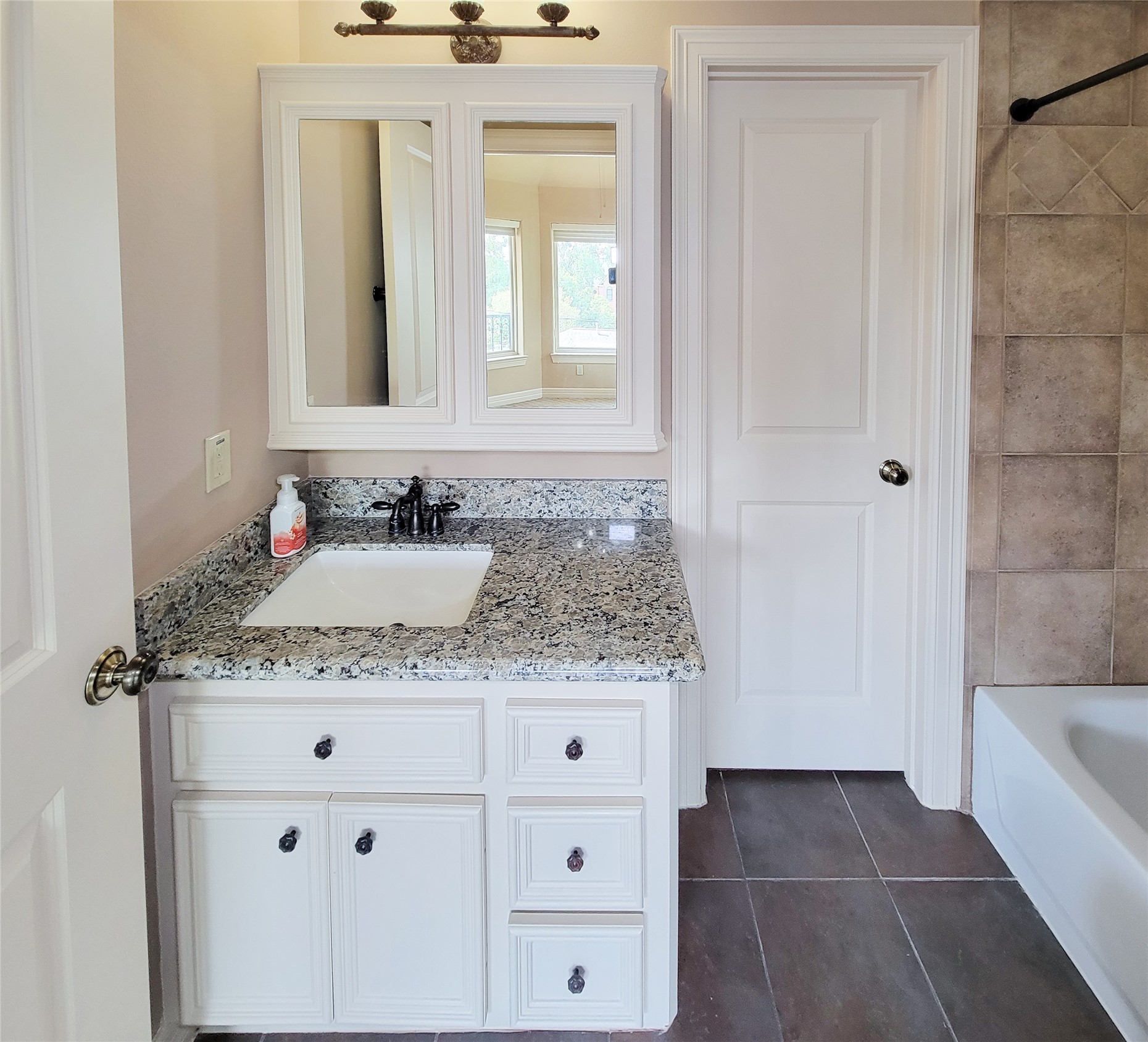 1118 Colonial Street Bellaire, TX 77401 - Photo 37 of 50 This private, fifth bedroom, bathroom features a modern vanity with granite countertops, ample cabinet storage, a large mirror, and a sleek faucet. The room has tiled walls and floors, and a shower-tub combo.