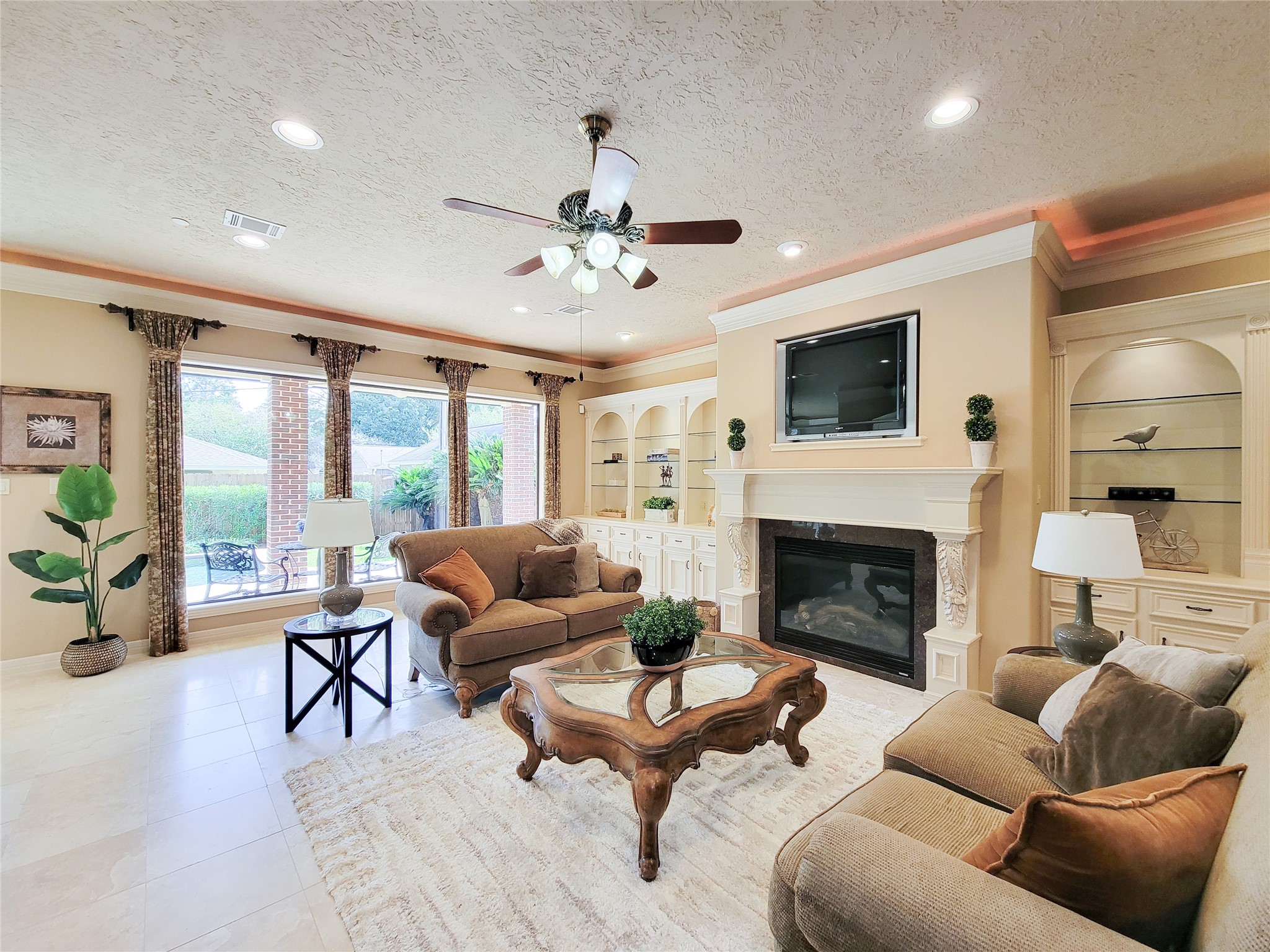 1118 Colonial Street Bellaire, TX 77401 - Photo 6 of 50 Gorgeous and spacious family room with recessed and rope lighting, built-ins with glass shelving, travertine flooring and gas log fireplace.