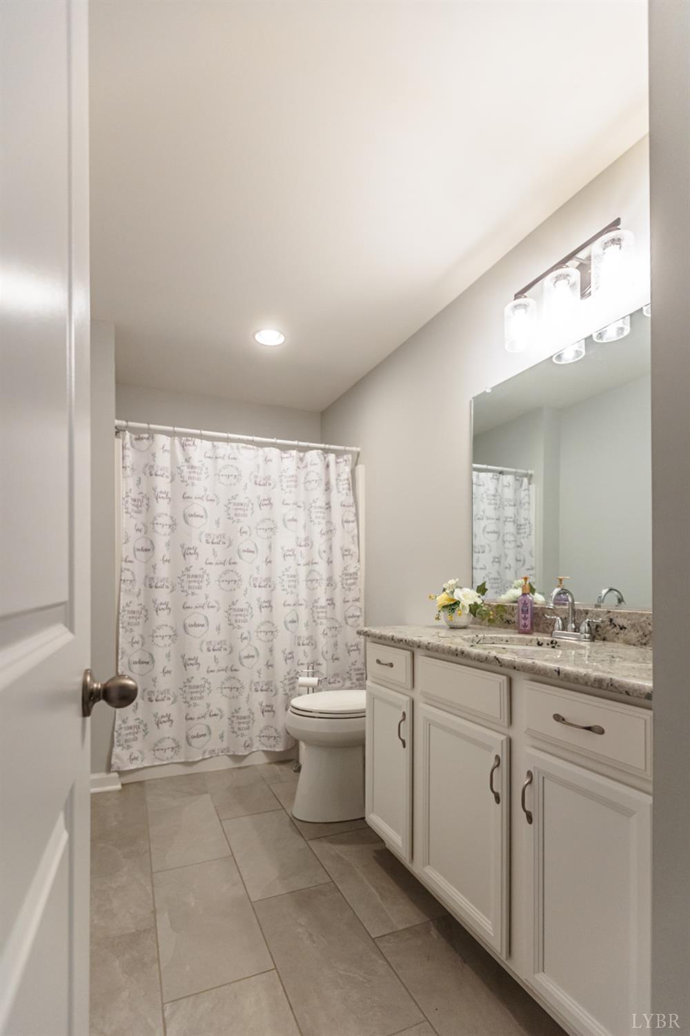 7099 Oakville Road Appomattox, VA 24522 - Photo 14 of 31 a spacious bathroom with a granite countertop sink a toilet and a mirror