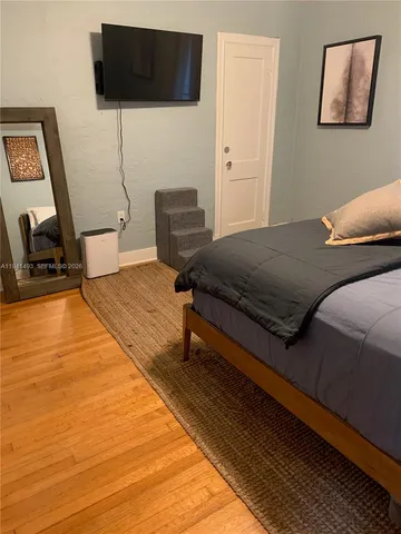 a bedroom with a bed a flat screen tv and guitar