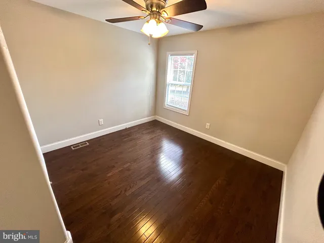 an empty room with wooden floor fan and windows