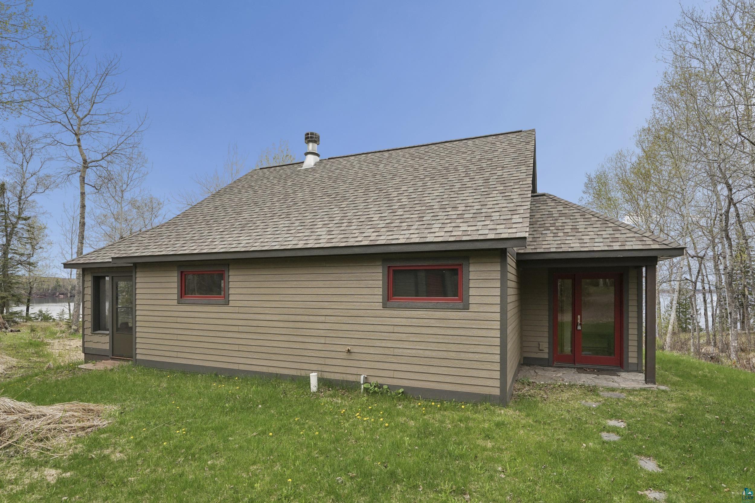 89095 West Romans Point Road Herbster, WI 54844 - Photo 9 of 30 Exterior featuring tan horizontal siding, a gray shingle roof, red-framed windows, and a red double-door entry
