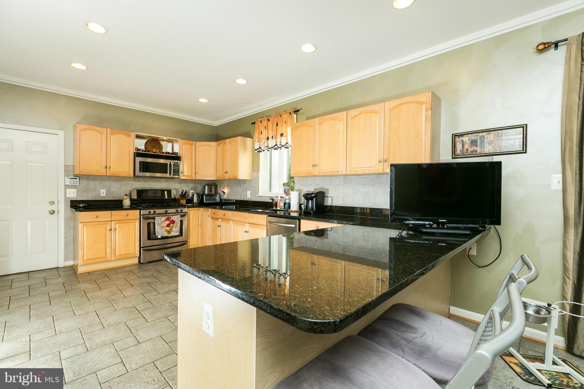 6824 Old Pimlico Road Baltimore, MD 21209 - Photo 8 of 20 a kitchen with stainless steel appliances granite countertop a stove top oven a sink a dining table and chairs