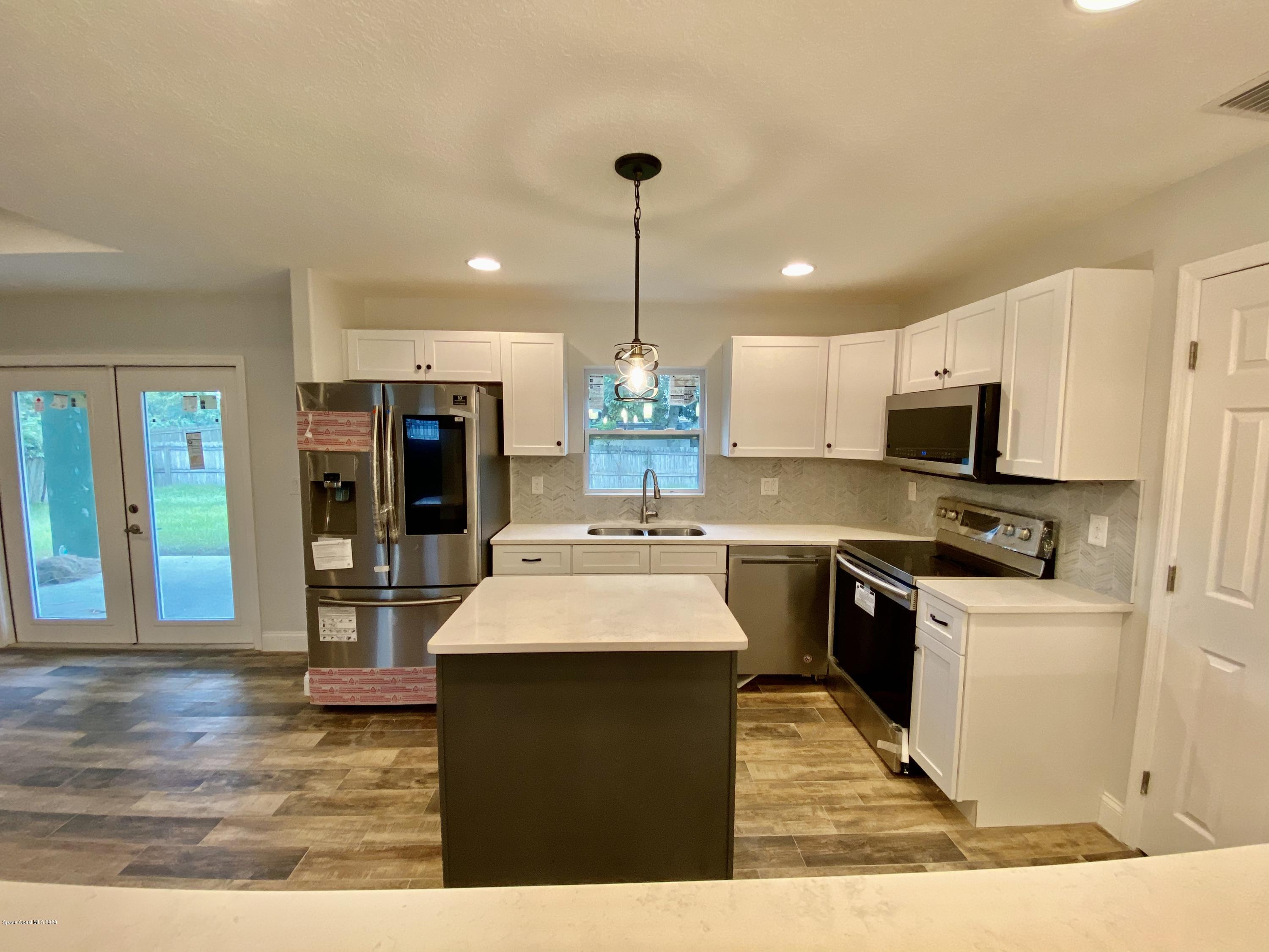 6444 Hudson Road Cocoa, FL 32927 - Photo 10 of 21 a kitchen with kitchen island granite countertop a stove top oven a sink dishwasher and a refrigerator with wooden floor