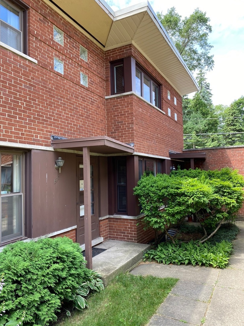 a front view of a house with a yard and potted plants