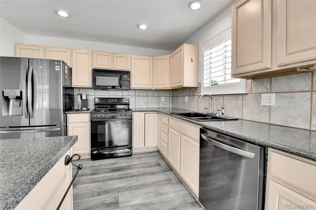 a kitchen with granite countertop a sink stainless steel appliances and cabinets