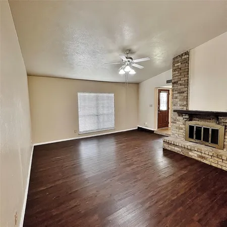 an empty room with wooden floor fireplace and windows