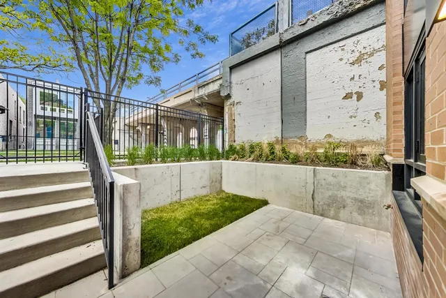 a view of an empty room with wooden floor and a kitchen