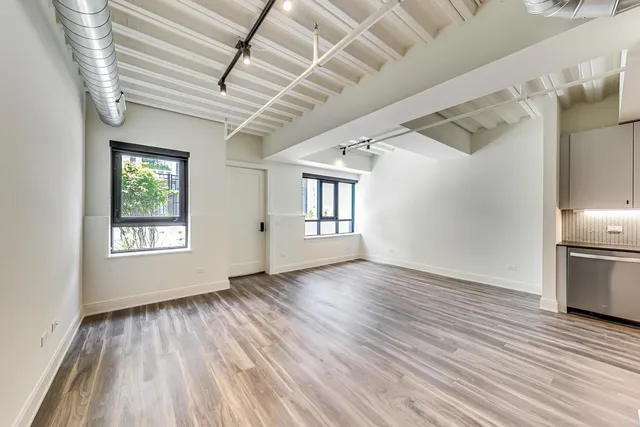 a view of an empty room with wooden floor and stairs