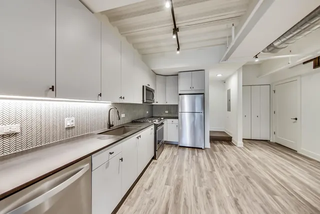 a view of a kitchen with wooden floor electronic appliances and stairs