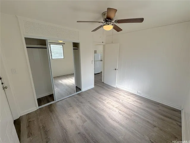 an empty room with wooden floor cabinet and windows